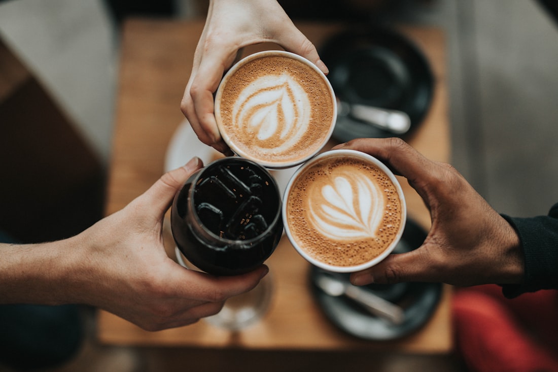Des mains qui trinquent avec des tasses de café